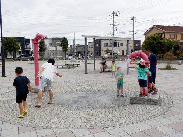 徒渉池で子どもたちが遊ぶ様子。2本のパイプの上部からシャワーのように水が出る装置です