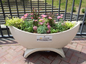 花が植えられた狸二条広場の船形コンテナの写真