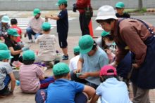 秋桜のメンバーさんが小学生に花植えを教えているところ