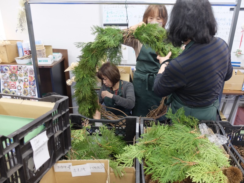 リース台にヒバのパーツを巻き付けている