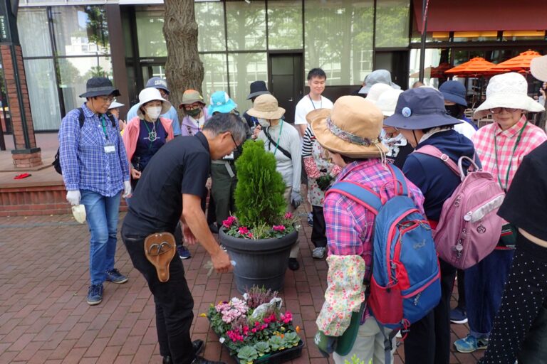 植替え後の見本のプランターについて説明している様子