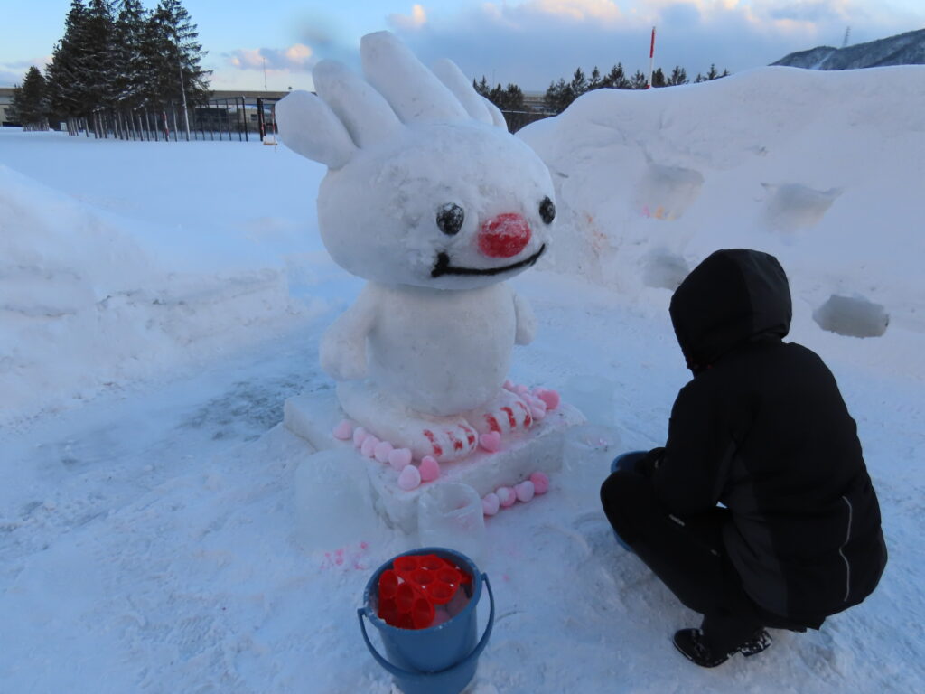 ていぬ君の雪像とハート形の雪玉の写真