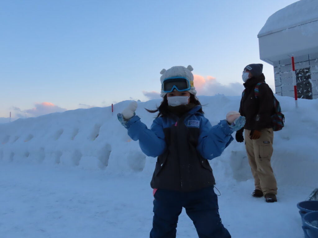 雪玉を手にポーズをとる子供の写真