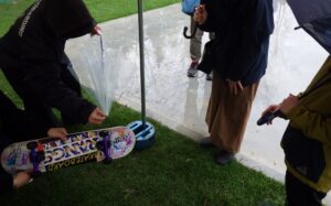 テントの中でスケボーの板の説明をしている写真