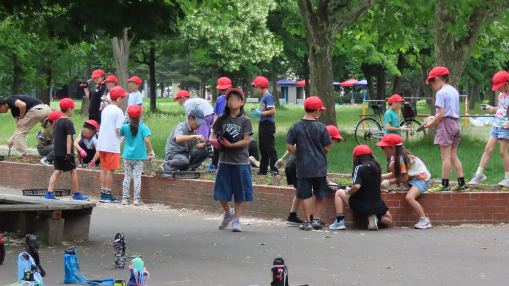 小学生たちと花を植えている写真