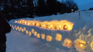 花を閉じ込めた氷の板や雪の壁に穴をあけてキャンドルを灯している写真