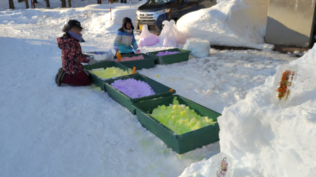 色のついた雪で雪玉を作っている写真