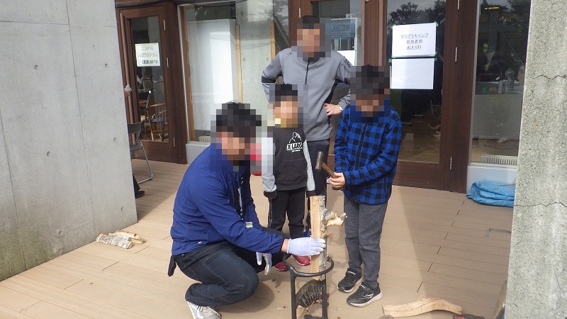 少年がハンマーを使って薪を割る様子