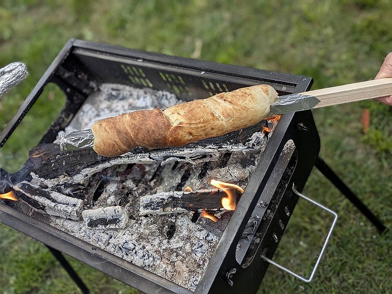 こねたパン生地を棒に巻き付けて薪で焼く様子