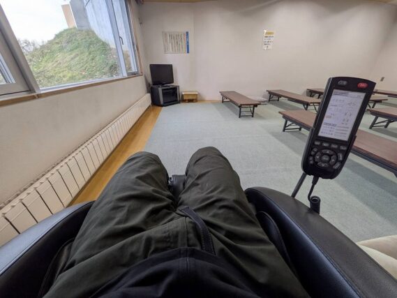 スタッフが新型マッサージチェアに座りマッサージを体験している様子。