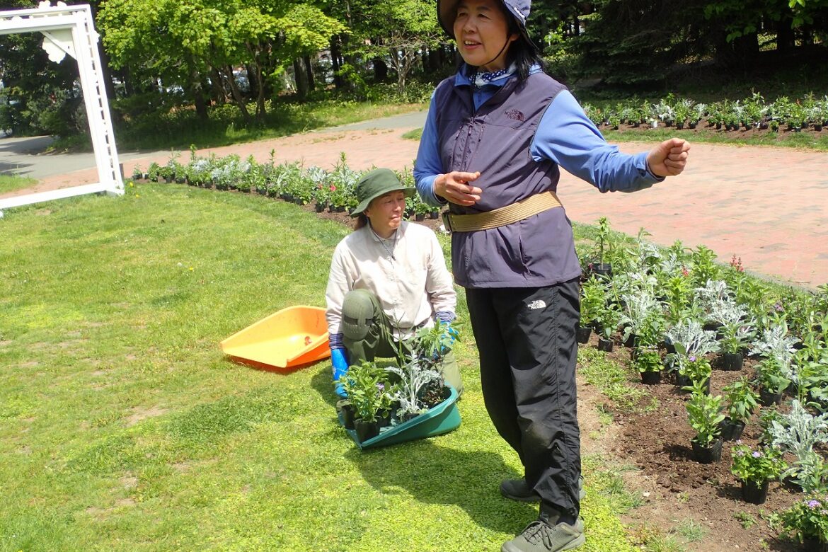 これから植える花苗が配置された花壇の前で植え方の説明をする講師