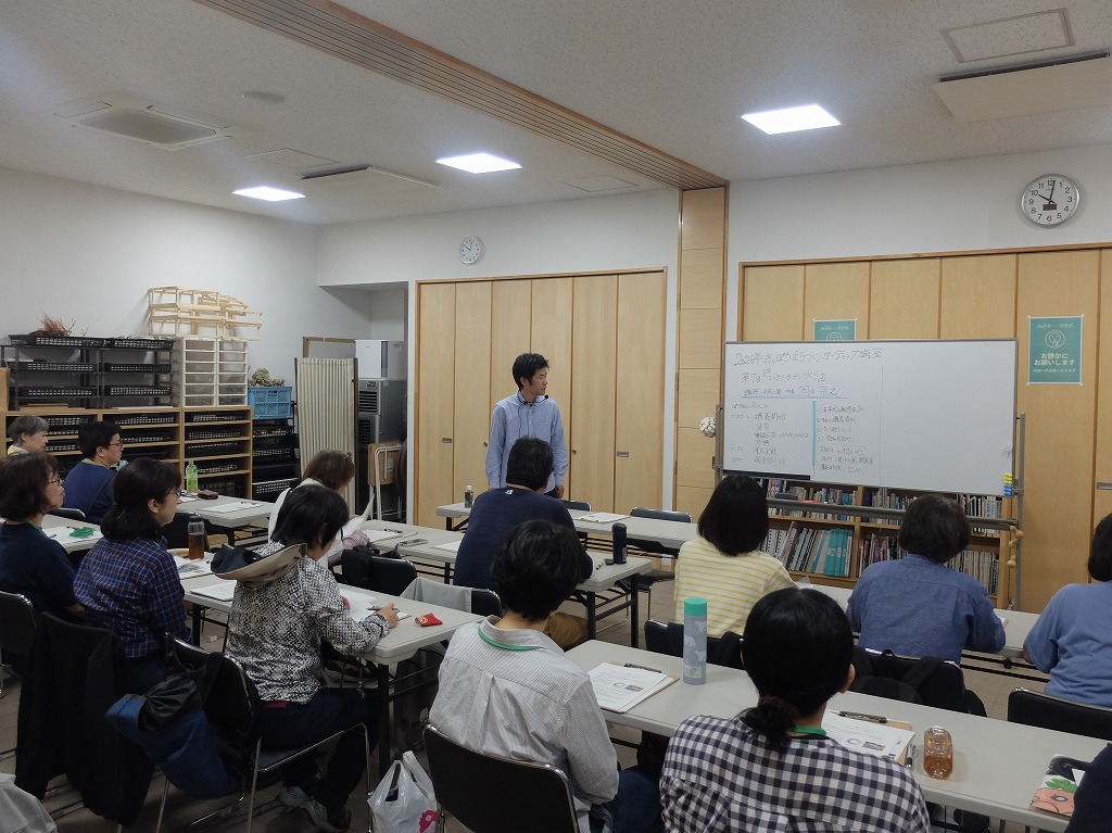 講義室で講師がホワイトボードを使用して18名の受講生を前に講義している様子