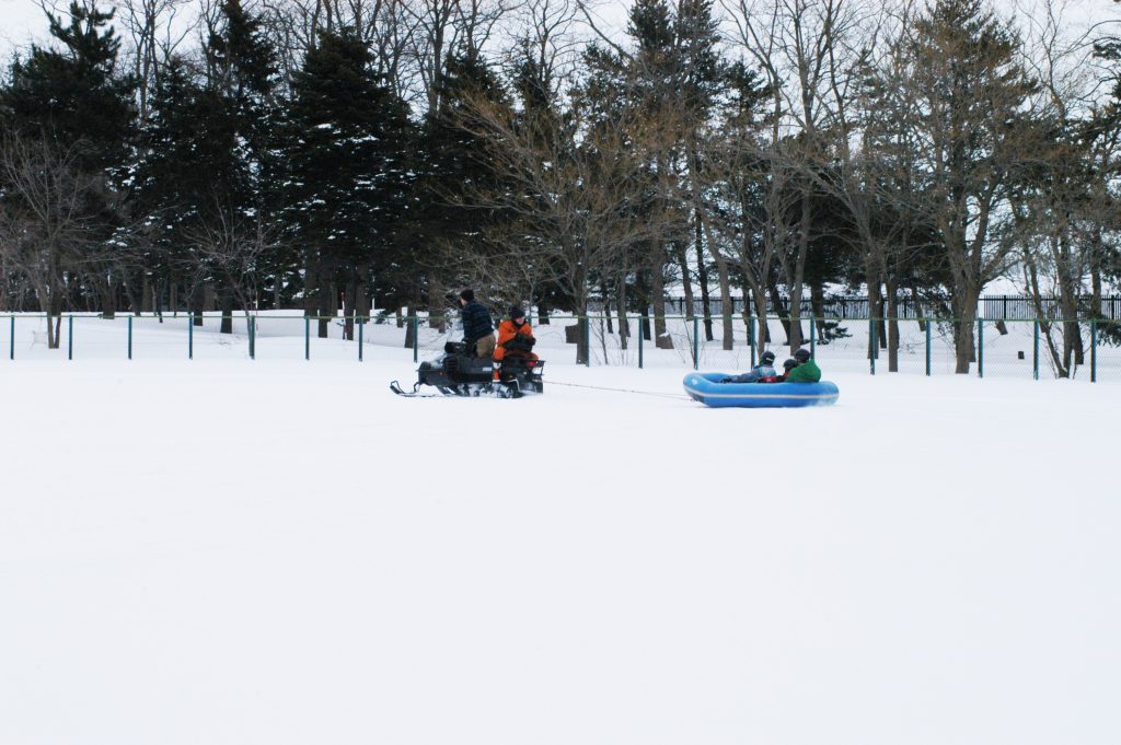 ラフティングボートの写真。スノーモービルで大きなゴムのボートを引っ張っています。