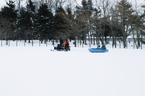 ラフティングボートの写真。スノーモービルで大きなゴムのボートを引っ張っています。