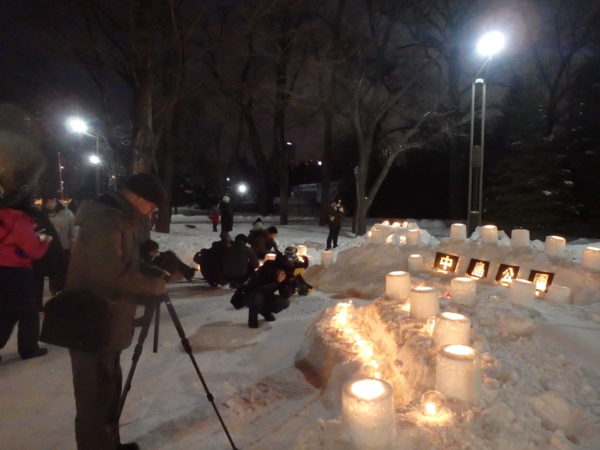 点灯したスノーキャンドル会場や点灯するキャンドルの様子をカメラで撮影する来場者