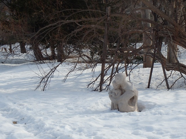 足元半分くらい雪の中に埋まっている、彫刻「母と子の像」