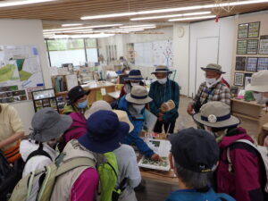 管理事務所で花の作りの説明を受ける参加者の皆さん