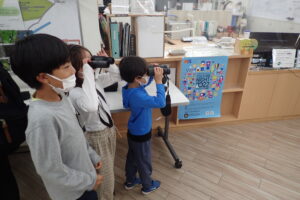 双眼鏡をのぞいてみる小学生