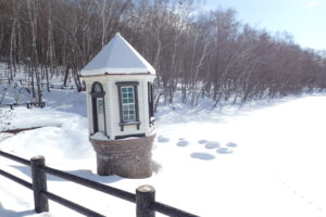 赤い屋根に雪がかぶった取水塔