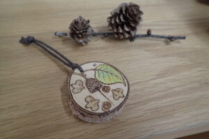 樹の輪切りにバーニングで絵を付けたストラップ