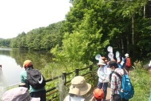 池の周りでトンボを探す団員と保護者達