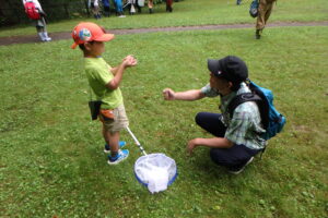 捕まえたトンボを網から出す親子
