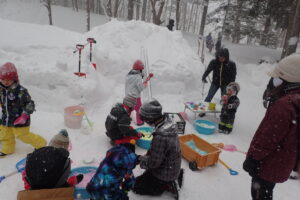 親子連れが雪の中で雪で遊んでいる