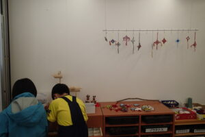 毛糸と枝で作った雪の結晶を飾った部屋で工作する子ども