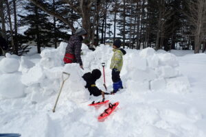 親子連れが雪の中で雪で遊んでいる