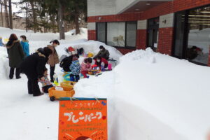 親子連れが雪の中で雪で遊んでいる