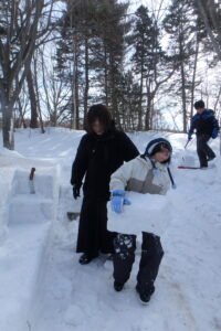 雪のブロックを運ぶ参加者
