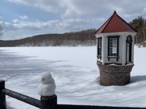 赤い屋根の取水塔と手前の柵の上に作られた雪だるま