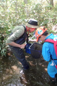 ボランティアさんに魚の取り方を教わる子ども