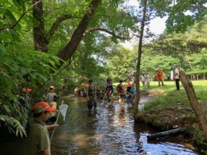 川の中でたも網を持った子どもたち