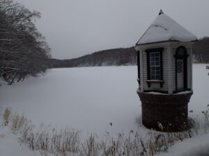 雪に覆われた池と赤い屋根の取水塔