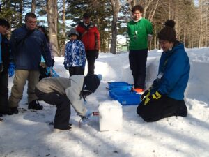 雪のブロックを切り出す子ども