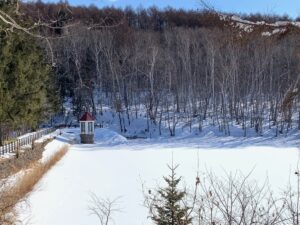 赤い屋根の取水塔と雪に覆われた池