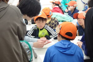 三角紙にトンボを収める方法を学ぶ子供