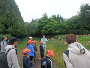 草地で説明をうける保護者と団員