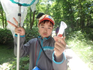 捕まえたトンボを手に持った子供