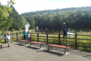 池の周りでトンボとりする子どもたち