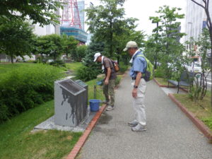 開拓の広場の説明板を清掃するお助け隊
