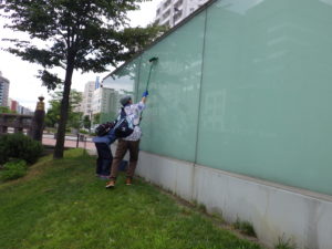 開拓の広場のガラスウォールを清掃するお助け隊