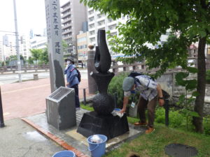開拓の広場の建設の地碑を清掃するお助け隊
