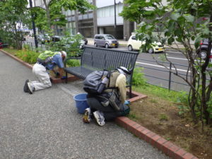 7月22日のお助け隊の活動でベンチの下の除草をする様子