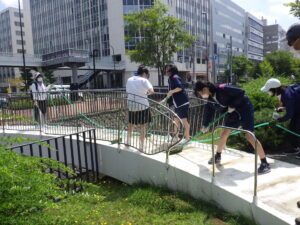 7月27日の活動でスノーリングの清掃をするお助け隊と高校生