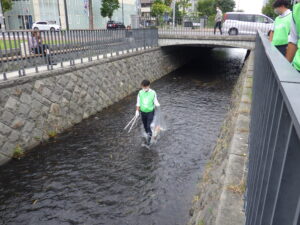 8月30日に川の中のごみ拾いをする企業ボランティア