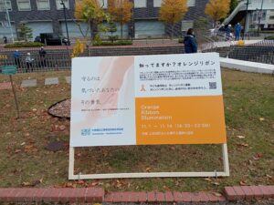 まんなか広場に設置されたオレンジリボンイルミネーションライトアップの看板