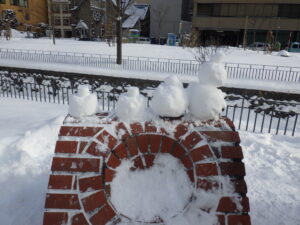 北2条のレンガの作品の上に載せられた雪だるまの画像