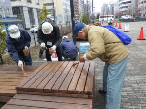 4月19日に狸二条広場の縁台の塗装をするお助け隊のメンバー